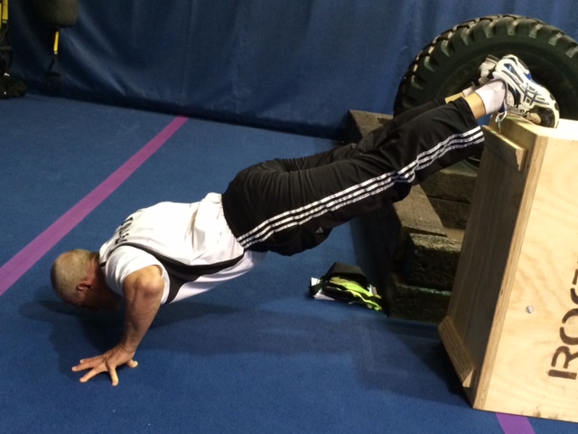 Wally, 65, performing a challenging decline push-up to showcase advanced fitness at Body By Wally in Augusta.