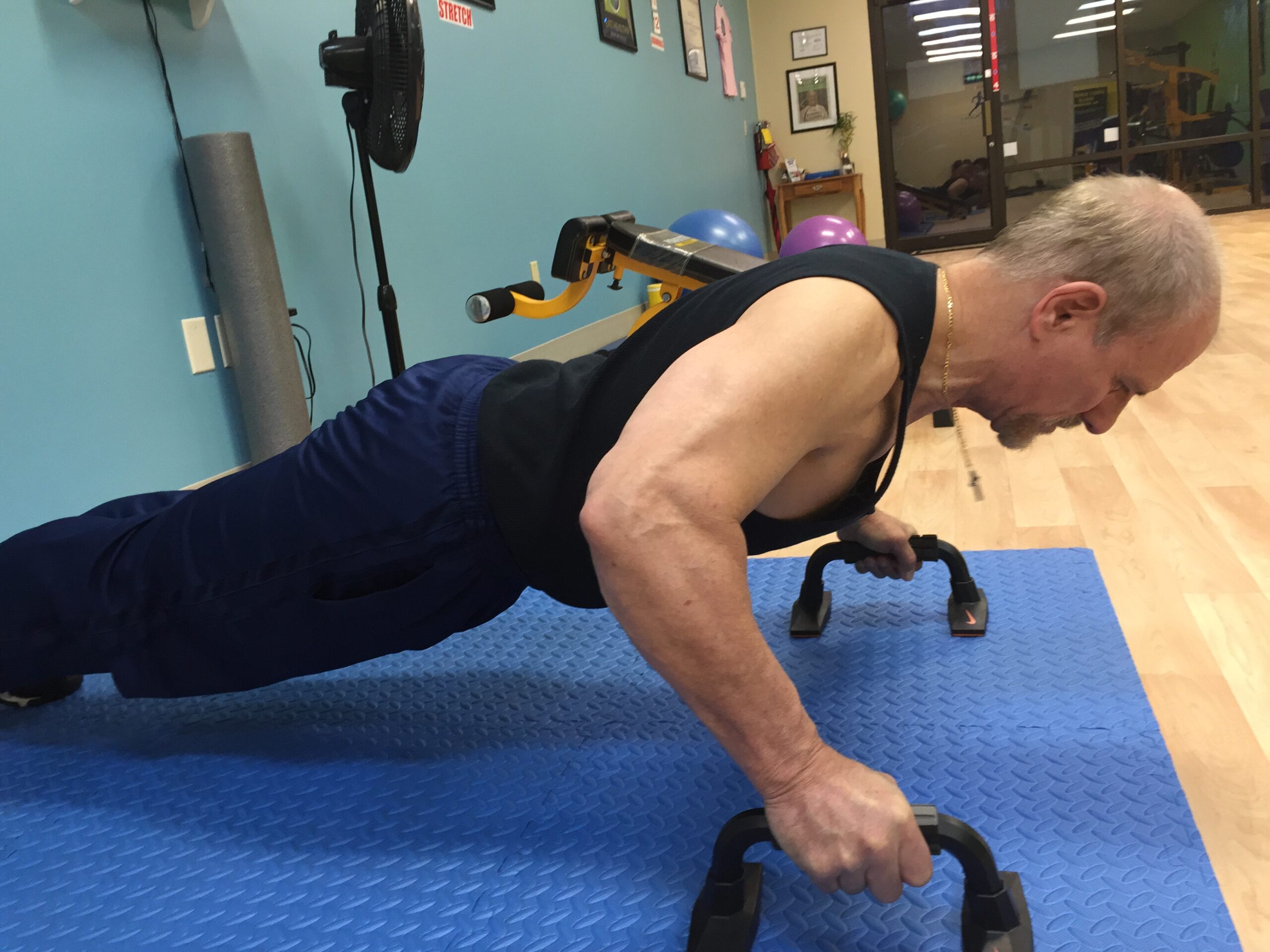 Wally, at 65 years old, doing a push-up to demonstrate strength and fitness at Body By Wally in Augusta.